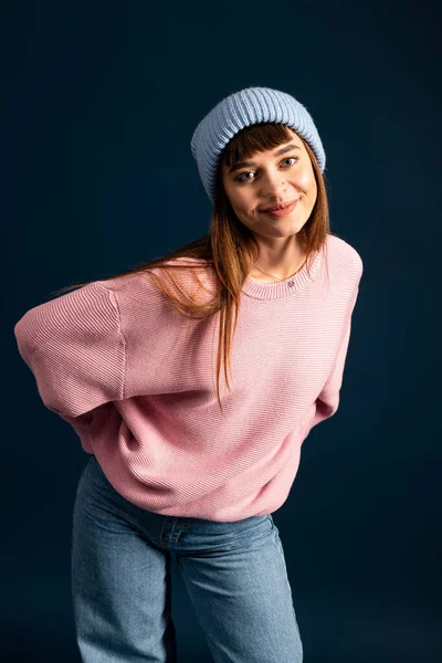 Mujer joven con un atuendo acogedor sonríe mientras posa juguetonamente, capturando la esencia del calor. - foto de stock
