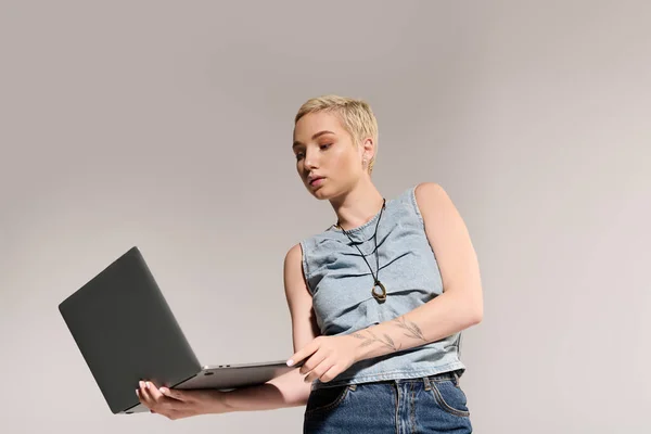 Mujer joven de moda se centra en su computadora portátil, mostrando la moda y la creatividad en un espacio elegante. — Stock Photo