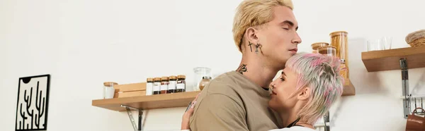 Молода пара ділиться теплими обіймами на своїй кухні, випромінюючи любов і щастя разом. — стокове фото