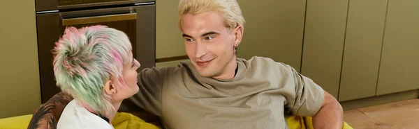 Una pareja cariñosa se relaja en un sofá, sonriendo y disfrutando de la compañía de los demás. - foto de stock