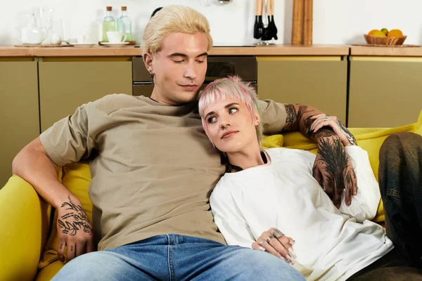 Liebendes Paar entspannt auf einer gelben Couch und teilt süße Momente in ihrem hellen, gemütlichen Wohnraum. — Stockfoto