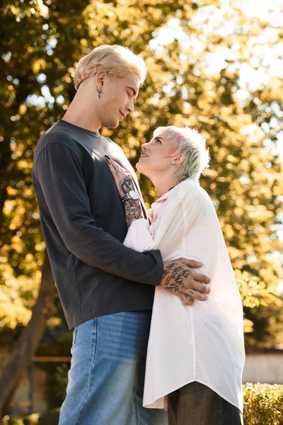 Ein Paar steht in einem sonnenbeschienenen Park und teilt einen freudigen, intimen Blick. — Stockfoto