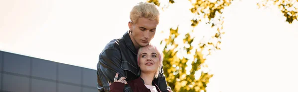 Una pareja amorosa comparte un momento alegre en un lugar soleado rodeado de árboles. - foto de stock