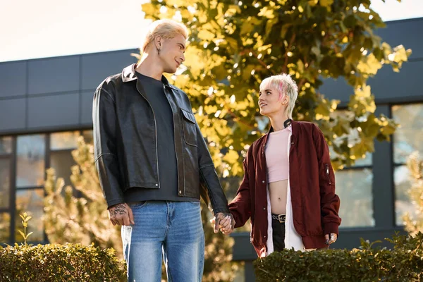 Двоє молодих коханців тримаються за руки, насолоджуючись прекрасним днем, оточеним зеленню та сонячним світлом. — стокове фото