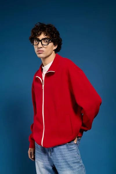 Um homem jovem e elegante exibe seu estilo em uma jaqueta vermelha ousada, exalando charme e confiança. — Fotografia de Stock