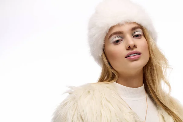 Блондинка демонстрирует свой зимний стиль и макияж во время ношения шубы и шляпы — стоковое фото