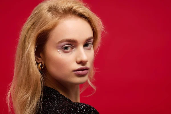 Una splendida giovane donna con un bel trucco posa con grazia su sfondo rosso — Foto stock