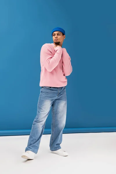 Un bel giovane uomo posa fiducioso in uno studio colorato, indossando abiti alla moda. — Foto stock