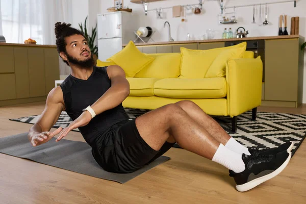 Un hombre atlético afroamericano con ejercicios de barba en casa, dedicado a un entrenamiento básico. - foto de stock