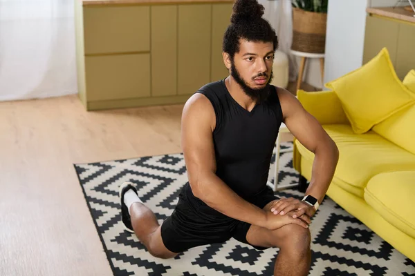 Спортивный человек занимается упражнениями на растяжку дома, демонстрируя самоотверженность и силу. — стоковое фото