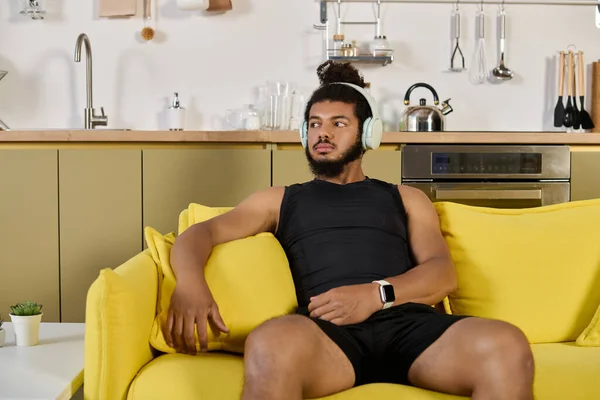 Athletic man takes a break from exercising at home while wearing headphones and looking relaxed. — Stock Photo