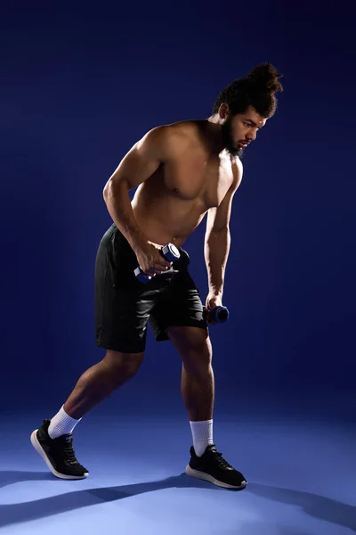 Athletic man with curly hair and a beard performs a workout with dumbbells. — Stock Photo