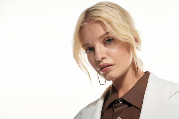 Jeune femme blonde dans une tenue élégante pose avec confiance sur un fond blanc. — Photo de stock