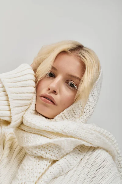 Una bella giovane donna bionda con ciglia bianche posa in un accogliente maglione a maglia in uno studio. — Foto stock
