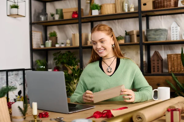 Молода жінка вдома сміється під час спілкування зі своїм ноутбуком в затишній, теплій атмосфері. — стокове фото