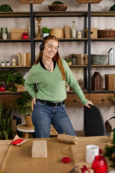 Молода жінка обіймає затишну атмосферу вдома, щасливо обгортаючи подарунки і слухаючи музику. — стокове фото