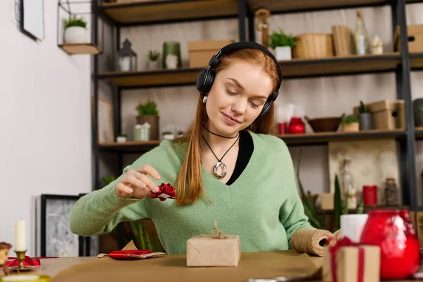Молода жінка насолоджується обгортанням подарунка в оточенні теплого і запрошеного домашнього середовища. — стокове фото