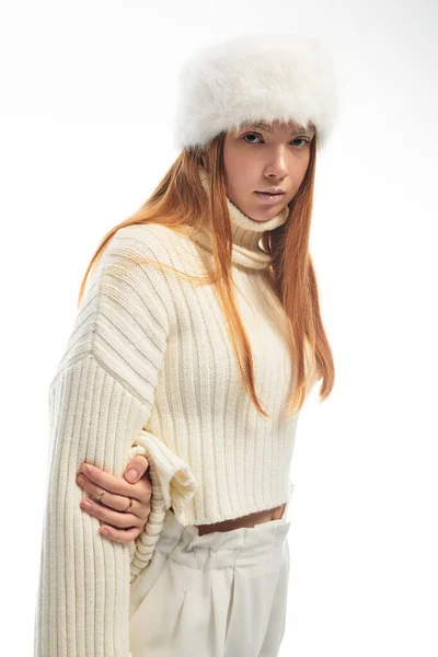Una joven pelirroja posa con estilo en un acogedor suéter y sombrero de piel, perfecto para vibraciones de invierno. - foto de stock
