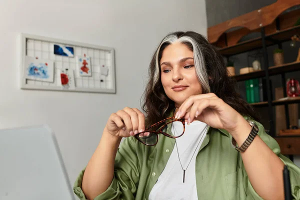 A woman with white forelock and blue eyes enjoys her cozy space while holding her glasses. — Stock Photo