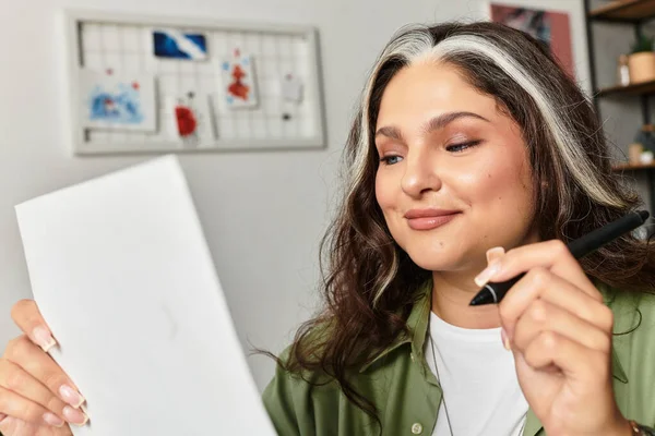 Жінка з білим передпліччям і блакитними очима посміхається, переглядаючи нотатки в її сучасній квартирі. — стокове фото