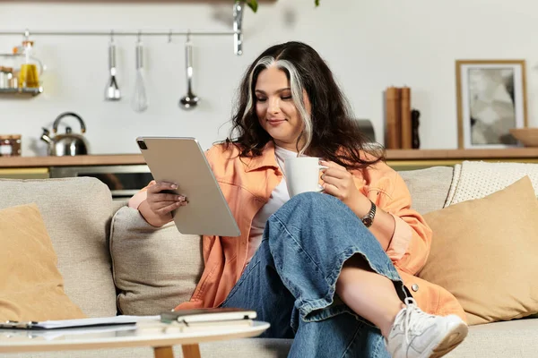 У стильній квартирі жінка з білою дитиною відпочиває з таблеткою і теплим напоєм. — стокове фото