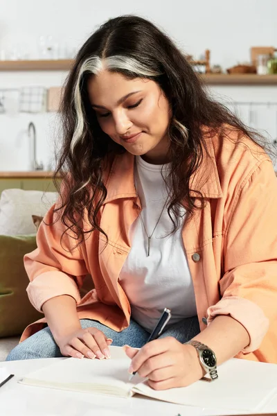 In a stylish apartment, a woman with a white forelock writes in her notebook with joy. — Stock Photo
