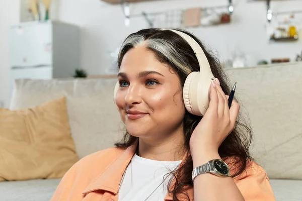 У затишній, сучасній квартирі жінка з білим димом посміхається, слухаючи музику. — стокове фото