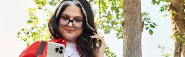 Молода жінка з білою виделкою використовує свій смартфон на відкритому повітрі серед природи, банер — стокове фото