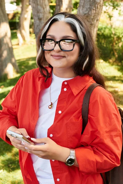 A young woman with a striking white forelock enjoys the outdoors, smiling joyfully. — Stock Photo