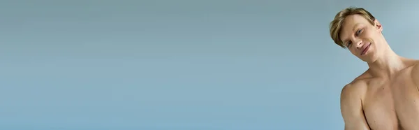 A young, handsome man poses confidently against a serene blue background. — Stock Photo