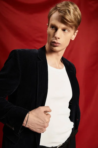 Ein junger Mann strahlt Charme und Zuversicht vor leuchtend rotem Hintergrund aus und verkörpert Männlichkeit. — Stockfoto