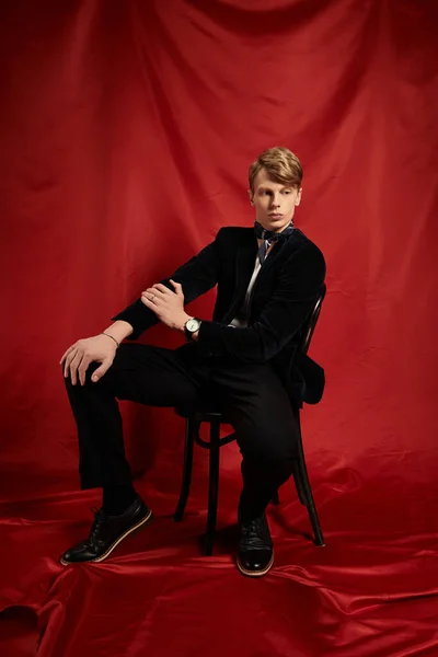 Красивий молодий чоловік демонструє сучасну мужність, сидячи впевнено, одягнений елегантно. — стокове фото