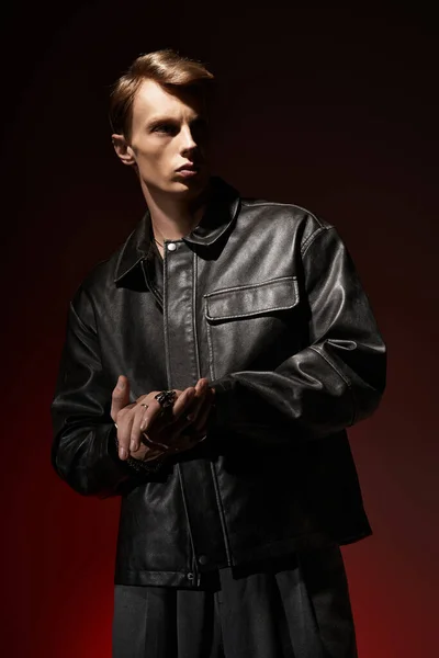 Молодий чоловік впевнено стоїть з гладкою шкіряною курткою, виключаючи привабливість і сучасний шарм. — стокове фото