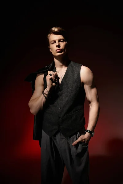 Красивий молодий чоловік демонструє свою привабливу присутність в сучасному вбранні під драматичним освітленням. — стокове фото
