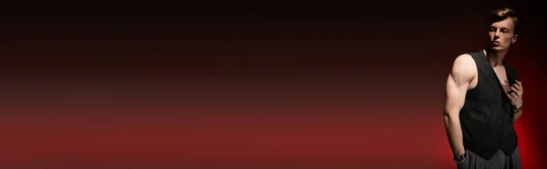 Красивый молодой человек излучает очарование в стильном наряде на драматическом фоне. — стоковое фото
