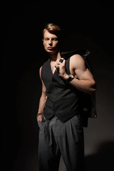 Молода, приваблива людина впевнено стоїть в тьмяній обстановці, виключаючи сучасну мужність. — стокове фото