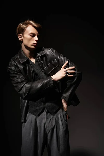 Молодой человек воплощает современную мужественность в стильной черной кожаной куртке, уверенно позируя. — стоковое фото