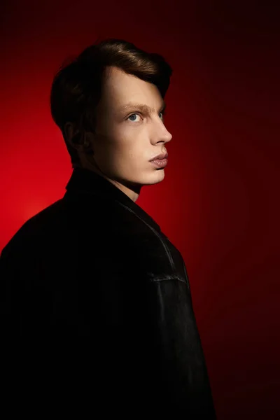 Красивий молодий чоловік впевнено стоїть у драматичному червоному світлі, втілюючи сучасну мужність. — стокове фото
