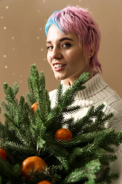 Joyful woman embraces winter greenery with oranges, radiating festive cheer. — Stockfoto