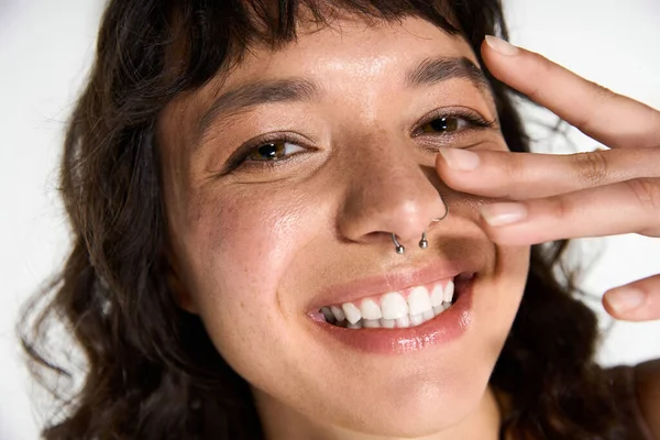 Una joven con un atuendo elegante muestra su hermosa sonrisa y gesto juguetón mientras posa. - foto de stock