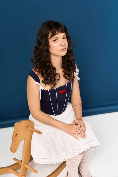 Молода красива жінка одягнена елегантно позує на коня-качалку в безтурботній обстановці. — стокове фото