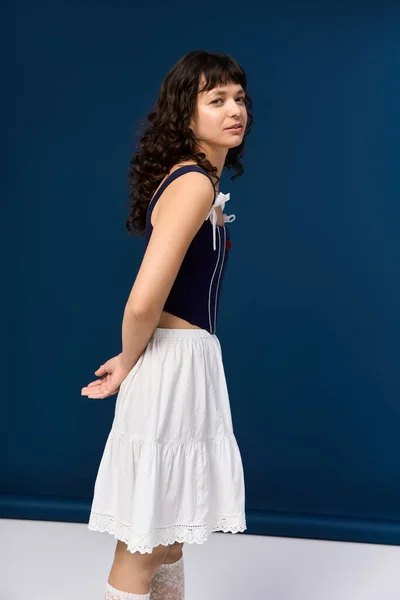 Красива жінка витончено стоїть, демонструючи свій стильний одяг, вражаючи грайливу позу. — стокове фото