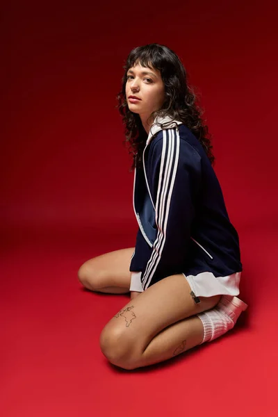 Молода жінка витончено на коліна, показуючи свій стильний одяг на сміливий фон. — стокове фото