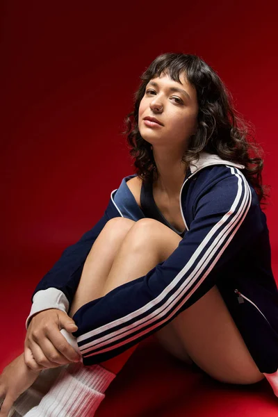 Eine schöne junge Frau sitzt anmutig auf dem Boden und prahlt mit ihrem stylischen Outfit. — Stockfoto