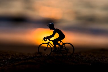 Gün batımında sahilde siluetleri bisikletçiler.