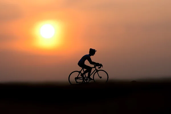 Siluetas ciclistas en la playa al atardecer . — Foto de Stock