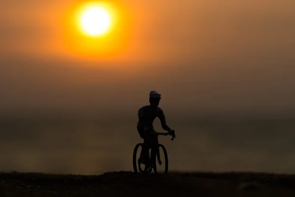 Silhuetas ciclistas na praia ao pôr do sol . — Fotografia de Stock