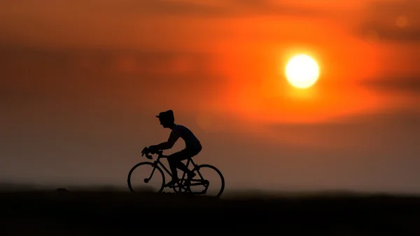 Silhuetas ciclistas na praia ao pôr do sol . — Fotografia de Stock