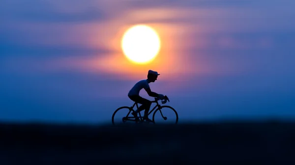 Siluetas ciclistas en la playa al atardecer . — Foto de Stock