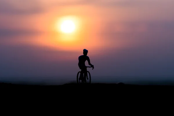 Silhuetter cyklister på stranden vid solnedgången. — Stockfoto